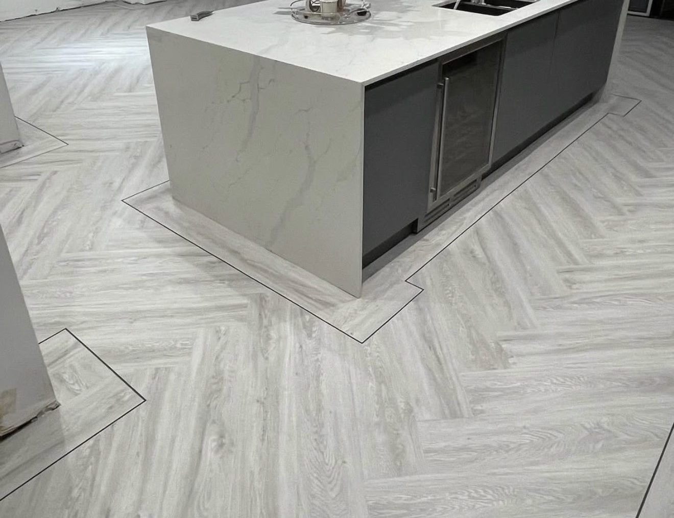 Whitewashed oak herringbone with a border and black strip cut around a kitchen island
